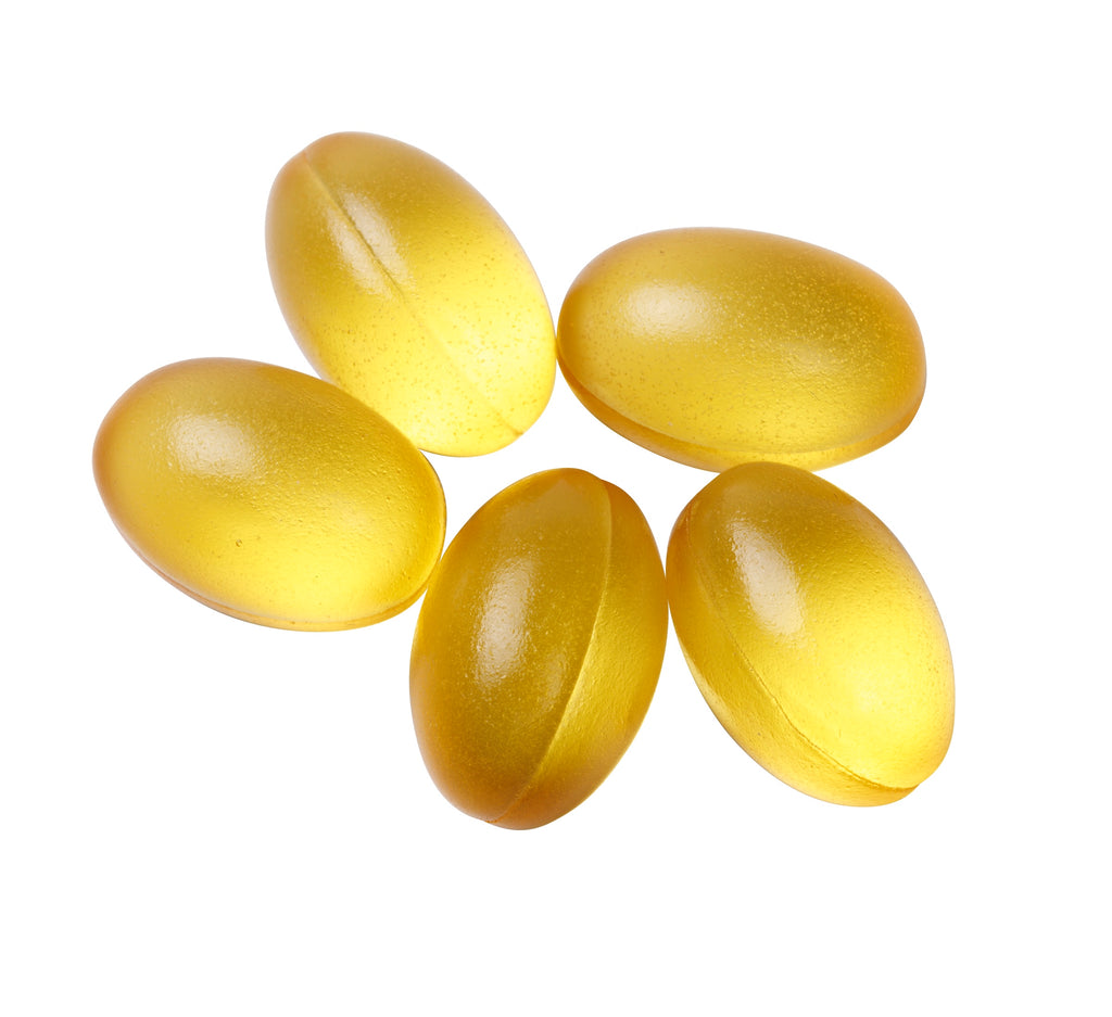 Five yellow gel capsules on a white background